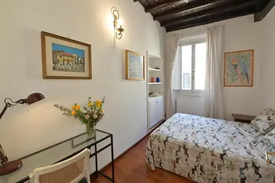 a bedroom with a bed and a table and a window at Domus Greci Piazza di Spagna in Rome
