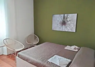 a bedroom with a bed and two white chairs at Casita in Rome