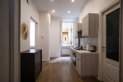 a kitchen with white cabinets and a black counter top at VT Cola di Rienzo Elegant Suites in Rome