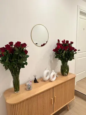 a table with two vases and red flowers on it at Vita Lux Vatican Suites in Rome
