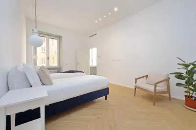a white bedroom with a bed and a chair at YCH-Spaceful apartment near Vatican in Rome