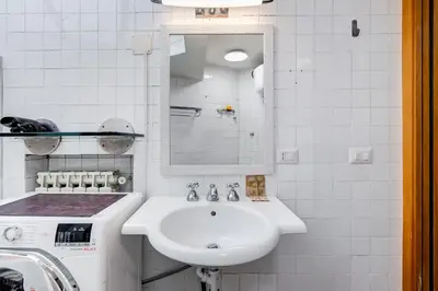 a white bathroom with a sink and a washing machine at Vivilo Collection - Macelli Spanish Steps Apartment in Rome