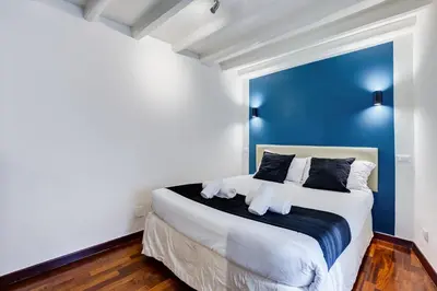 a bedroom with a large bed with a blue wall at Vivilo Collection - Macelli Spanish Steps Apartment in Rome