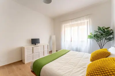 a white bedroom with a large bed with yellow pillows at Domus Citro, Cozy Flat in District Prenestina in Rome