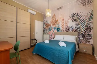 a bedroom with a blue bed and a wall with plants at GuestHost - San Giovanni Laterano Apartment in Rome