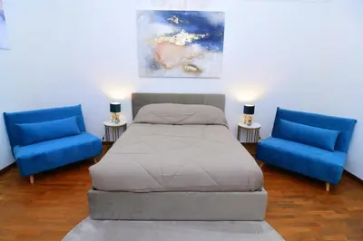 a bedroom with a bed and two blue chairs at Elegant Suite Colosseo in Rome