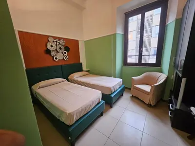 a bedroom with two beds and a chair and a window at San Lorenzo Accommodation One in Rome