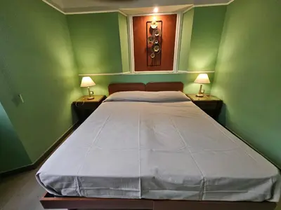 a green room with a bed with two lamps at San Lorenzo Accommodation One in Rome