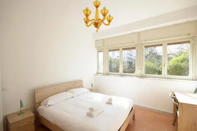 a bedroom with a bed with a chandelier and two windows at HC - Stadio Olimpico Huge Apartment NEW in Rome