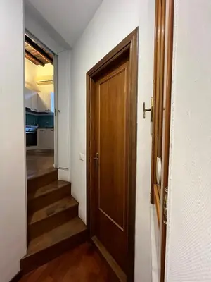 a hallway with a wooden door and a staircase at La Dolce Vita - Rione Campo Marzio the Beating Heart of Rome in Rome