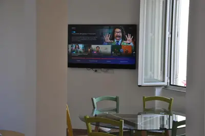 a television hanging on a wall with a table and chairs at Giulio al MAXXI Apartment Flaminio in Rome