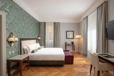 a hotel room with a bed and a desk at Rose Garden Palace Roma by OMNIA hotels in Rome