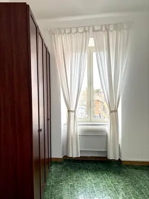 a room with a window with curtains and a green floor at Ad Maiora Domus in Rome