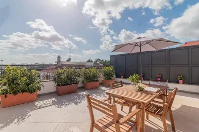 a patio with a table and chairs and an umbrella at Luxury Maison Dei Colli in Rome