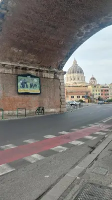 a bridge over a road with a building in the background at At the Pope's bridge in Rome