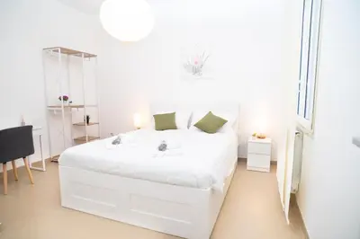 a white bedroom with a white bed and a chair at Modern two-room apartment for 2, 20 minutes from Termini in Rome