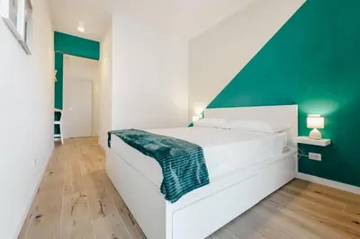 a bedroom with a white bed with a green accent wall at Smeraldo Vatican Moments in Rome