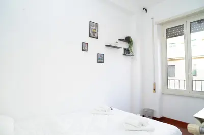 a white bedroom with a bed and a window at Modern and Central One-Bedroom, 10 min from Colosseum in Rome