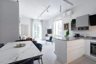a kitchen and living room with white cabinets and a table at Elegant Flat in Ponte Milvio in Rome