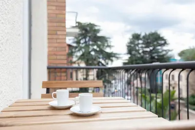 two coffee cups sitting on a wooden table on a balcony at Elegant Flat in Ponte Milvio in Rome