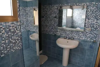 a blue tiled bathroom with a sink and a mirror at Super attico Eur in Rome