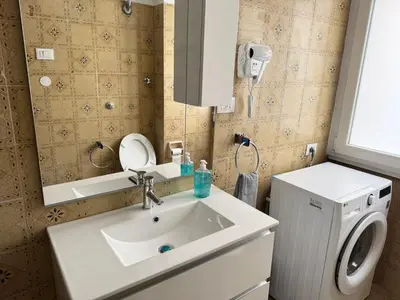 a bathroom with a sink and a washing machine at Piramide-Ostiense Two Bedroom Apartment in Rome