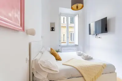 a white bedroom with a bed and a tv on a wall at iFlat New Boutique Apartment in Rome's Heart in Rome