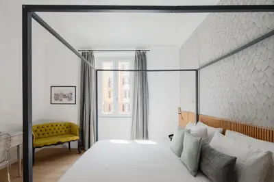 a bedroom with a large bed and a yellow chair at Aeterna Suites Roma in Rome