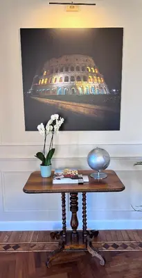 a table with a vase of flowers and a picture on the wall at Elegance and Style near St Peter's in Rome