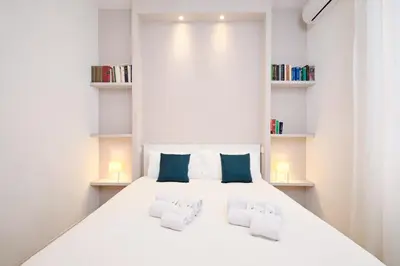 a white bedroom with a large white bed with blue pillows at Elegant Apartment near the Centre - Wi-Fi & Netflix Free in Rome