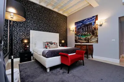 a bedroom with a large bed and a red chair at Sistina Twentythree luxury rooms in Rome
