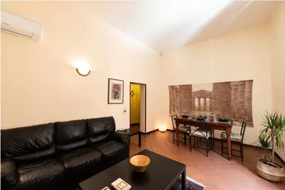 a living room with a black leather couch and a table at Secret place in the heart of ancient Trastevere in Rome