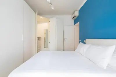 a bedroom with a white bed and a blue wall at Appartamento Elegante e Luminoso con Metro Vicina in Rome