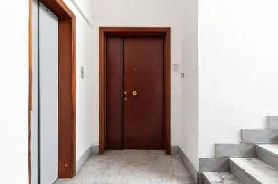 a brown door in a white room with stairs at Garbatella Appartamento Moderno Relax e Comfort in Rome