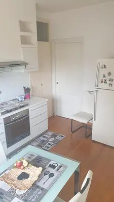 a white kitchen with a table and a refrigerator at Villa Domus Roma in Rome