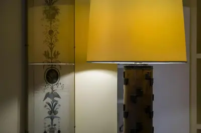 a lamp with a yellow shade next to a wall at Elegantis Monti Royal Apartment with private terrace in Rome