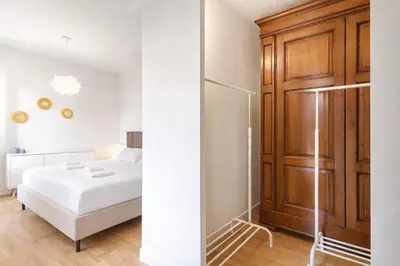 a bedroom with a white bed and a wooden cabinet at Elegantis Monti Royal Apartment with private terrace in Rome
