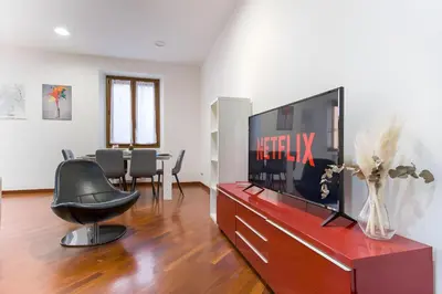 a living room with a flat screen tv and a chair at Elegantis San Giovanni Suite - Chic Apartment with Bathtub Near Historic Center, Metro & Tram Nearby in Rome