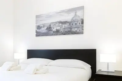 a bedroom with a white bed with two lamps at Elegantis San Giovanni Suite - Chic Apartment with Bathtub Near Historic Center, Metro & Tram Nearby in Rome