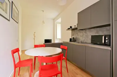 a kitchen with a table and red chairs in a room at La Casa di Chantal in Rome