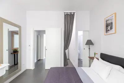 a white bedroom with a bed and a mirror at Trastevere Modern 4BR 4baths, WIFI, AC, custom kitchen, living room in Rome