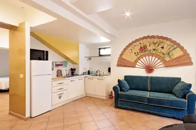 a living room with a blue couch and a kitchen at TrastevereHome - Secret Balcony in the Heart of Rome Trastevere in Rome