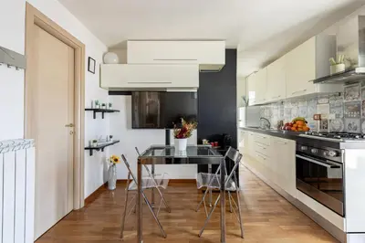 a kitchen with white cabinets and a table with chairs at Hostly-Salotti Terrace Suite-20min to Vatican in Rome