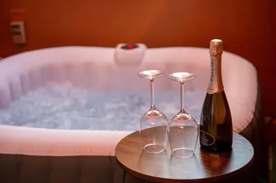 a bottle of champagne and two glasses on a table next to a bath tub at Welcoming Vatican Garden Home - with Hot Hub in Rome