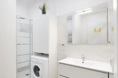 a white bathroom with a washing machine and a sink at central basic apartment in Rome