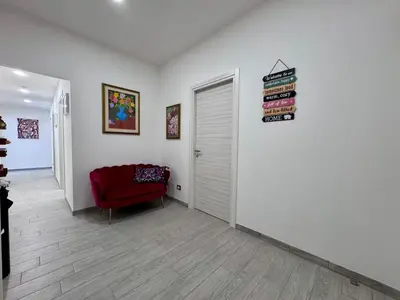 a living room with a red chair and books on the wall at Costabella Guest House in Rome