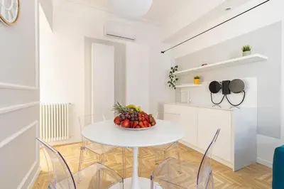 a white dining room with a white table and chairs at Hostly-Puccini Luxury Home-Near Colosseum & Trevi in Rome
