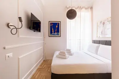 a white bedroom with a bed and a window at Hostly-Puccini Luxury Home-Near Colosseum & Trevi in Rome