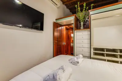 a bedroom with a bed with white sheets and a tv at Fico Giallo - Piazza Navona Apartment in Rome
