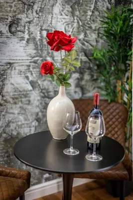 a vase with a rose and two glasses on a table at Lyo Sky Rooms in Rome